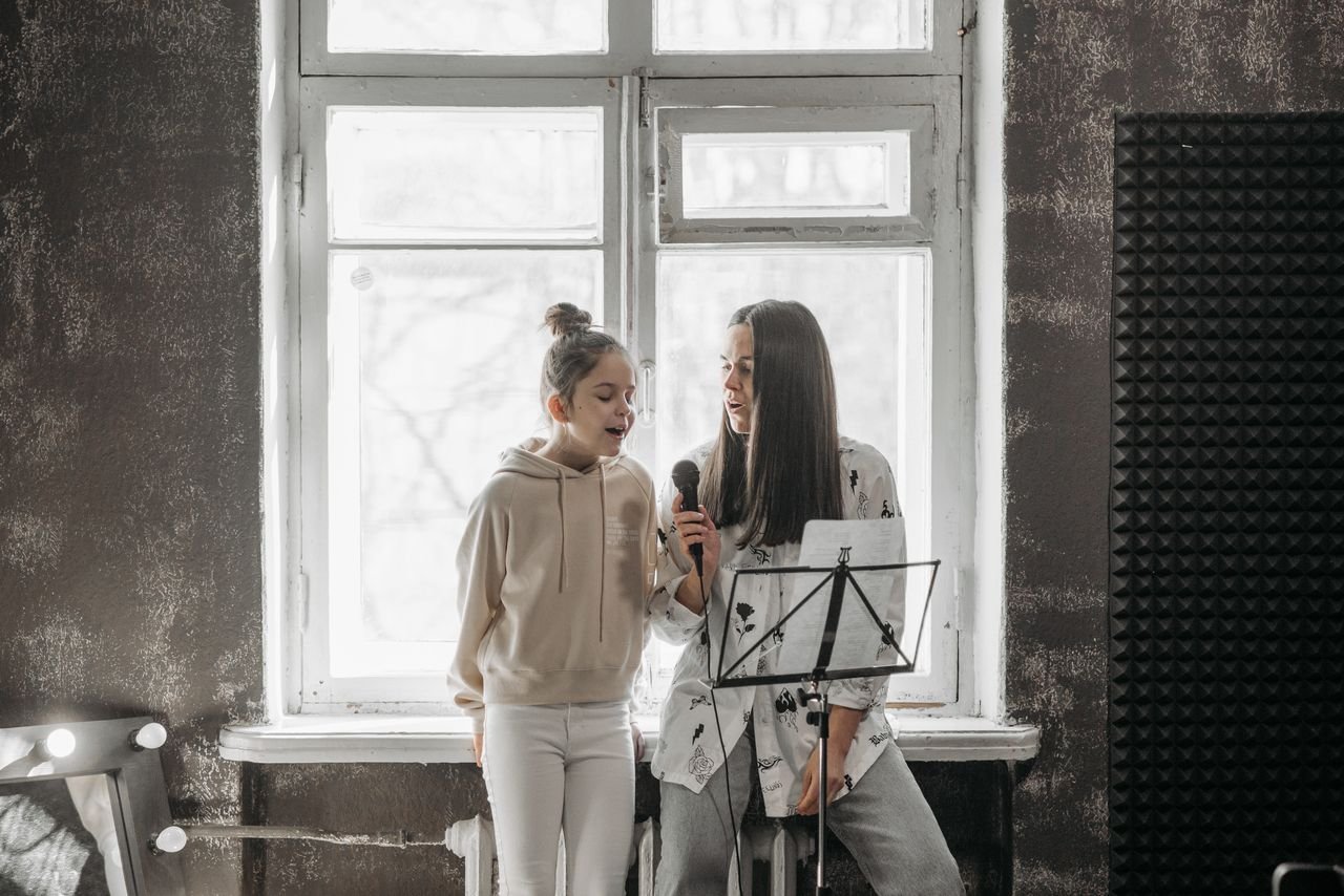 The Art of Drawing Readers In: Your attractive post title goes here A young girl and her teacher practicing singing in a music studio.