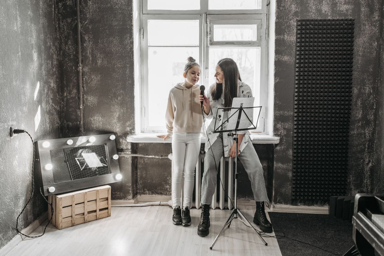 Mastering the First Impression: Your intriguing post title goes here A teenager and teacher singing in a modern studio, enhancing vocal skills.